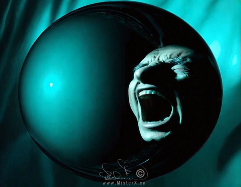 Image of a man's screaming face that appears to be trapped within a glass turquoise sphere.